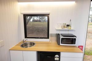 a small kitchen with a sink and a microwave at McCabe Farm Cabin by Tiny Away in Brookton