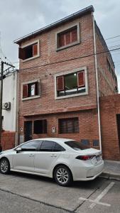 a white car parked in front of a brick building at Hospedaje Familiar Janaq Pacha in San Salvador de Jujuy