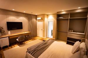 Un dormitorio con una cama, un escritorio y un televisor. en Morada Pedra Branca boutique Hotel, en Balneário Camboriú