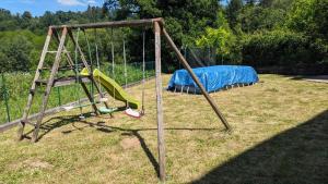 an old swing set with a blue tarp on a yard at Logement à Brive proche centre-ville et campagne - climatisation, Wifi, coin exterieur et parking privés in Brive-la-Gaillarde +5 photos
