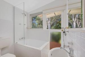 a white bathroom with a shower and a sink at 29 Flower Cct, Akolele in Central Tilba +34 photos