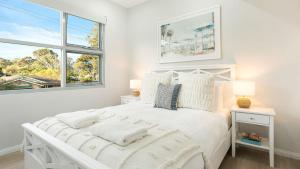 a white bedroom with a white bed and two windows at Elliniko in Callala Beach +15 photos