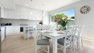 a kitchen and dining room with a white table and chairs at Elliniko in Callala Beach