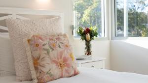 a bedroom with a bed with a pillow and a vase of flowers at Elliniko in Callala Beach