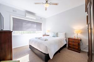 ein weißes Schlafzimmer mit einem Bett und einem Fenster in der Unterkunft Rosewood Cottage - Stroll to Central, Cosy Escape in Dubbo
