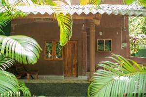 a house with a wooden door and some palm trees at Silent Bungalow in Udawalawe