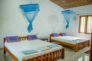 two beds in a room with blue umbrellas at Silent Bungalow in Udawalawe
