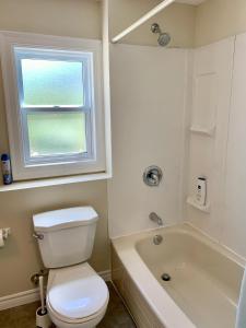 a bathroom with a toilet and a tub and a window at Faithful Home in Halifax +2 photos