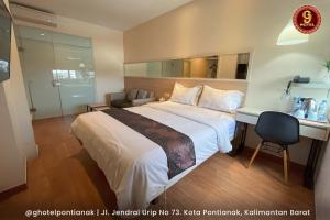 a hotel room with a large bed and a desk at G-Hotel Pontianak in Pontianak