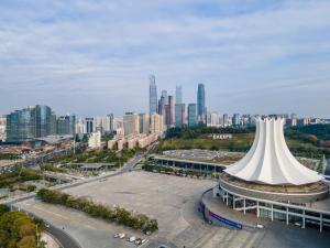 a large white building with a city in the background at Echarm Hotel Nanning the MixC Exhibition Center Metro Station in Nanning