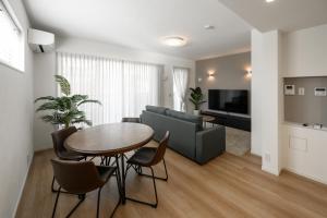 una sala de estar con una mesa y un sofá en Araha Beachway Inn, en Chatan