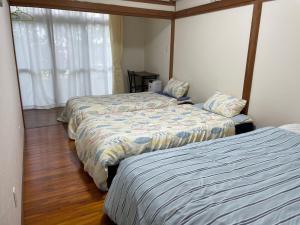 a bedroom with two beds and a window at Kami House in Amami