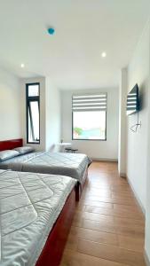 a bedroom with two beds and a window at Khách sạn triệu nguyễn in Buôn Kô Sir