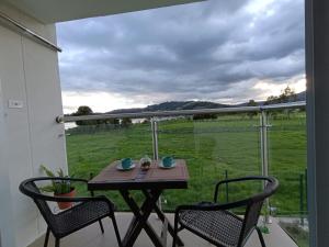 a table and chairs on a balcony with a view of a field at Arama Apartamento Boutique in Paipa