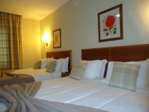 Habitación de hotel con 2 camas con sábanas blancas en Hotel Pombeira en Guarda