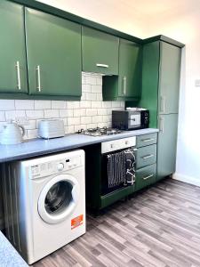 a kitchen with green cabinets and a washing machine at Spacious 3 Bdrm Close To Beach in Blythe +3 photos
