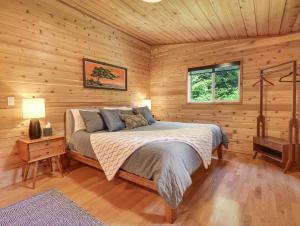 ein Schlafzimmer mit einem Bett in einer Holzhütte in der Unterkunft Woods Waves: Luxury Coast Cabin King Beds Pets in Tillamook