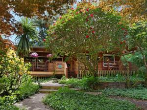 einen Garten mit einem Haus mit einem Baum mit roten Blumen in der Unterkunft Woods Waves: Luxury Coast Cabin King Beds Pets in Tillamook