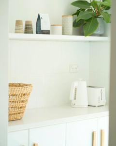a white kitchen shelf with a toaster and a plant at Villa Muraka Kalbarri in Kalbarri +20 photos
