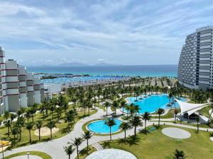 an aerial view of a resort with a pool and palm trees at Happy Beach Seaview Condotel at The Arena Cam Ranh Resort in Cam Ranh