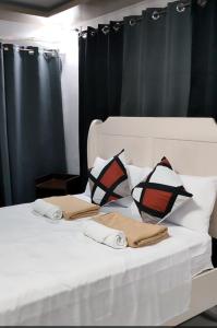 a white bed with black curtains and pillows on it at Pacifico's Hostel in Barili