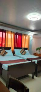 two beds in a room with colorful curtains at Pacifico's Hostel in Barili