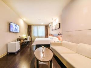 une chambre d'hôtel avec un canapé et un lit dans l'établissement Jinjiang Inn Select Wuhan Xinhua Road Xiehe Hospital, à Wuhan