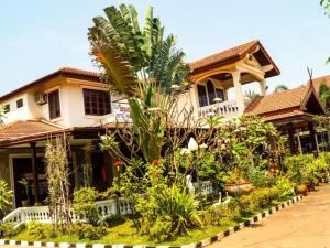 a house with a palm tree in front of it at Champa Residence Hotel in Pakse