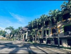 a large building with palm trees next to a street at Hotel Augusta Garut in Garut