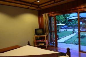 a bedroom with a bed and a tv and a window at Baan Aew Pai in Pai
