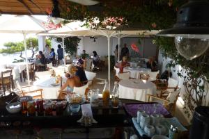 Agistri Club Hotel في Skliri: مطعم بالطاولات والناس جالسين على الكراسي