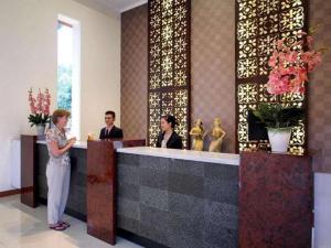 a woman standing at a reception desk in a lobby at The Arnawa Hotel in Pangandaran