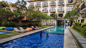 una piscina d'albergo con due bambini che giocano dentro di The Aroma's of Bali Hotel & Residence a Legian