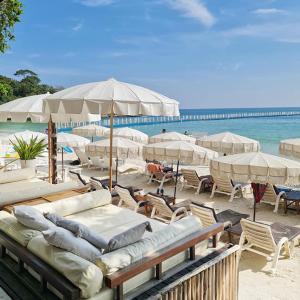 a beach with chairs and umbrellas and the ocean at Sawasdee Coco Resort in Ko Samed
