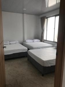 drei Betten in einem Zimmer mit Fenster in der Unterkunft Casa Acacías Meta con Piscina y Jacuzzi in Acacías