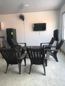 ein Zimmer mit schwarzen Stühlen und einem Fernseher an der Wand in der Unterkunft Casa Acacías Meta con Piscina y Jacuzzi in Acacías