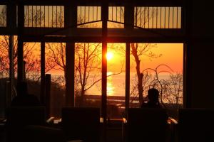 a sunset seen through a window with people sitting in chairs at Hotel Shiretoko in Shari