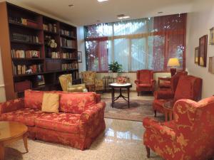 a living room with red furniture and bookshelves at Hotel Gama in Melzo