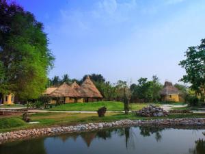 a group of huts with a pond in front at Tammarene Villa in Ban Tha Khoei