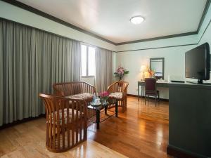 a living room with a table and chairs and a television at Grand Plaza Hotel in Hat Yai
