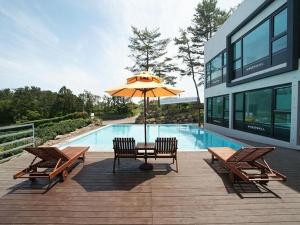 a table and chairs with an umbrella next to a pool at Nine Spavill Resort in Kwangnyŏng-ni