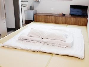 渡嘉敷村HOTEL KANALOA的一张白色的床,坐在房间里