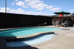 una piccola piscina con tavolo, sedie e ombrellone di Oxford Court Motel a Nelson