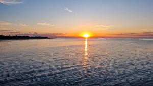 a sunset over the water with the sun setting at Fewo 2 Stueven im Reetdachhaus Fewo cc in Kolpinsee