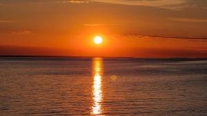 a sunset over the ocean with the sun setting at Fewo 2 Stueven im Reetdachhaus Fewo cc in Kolpinsee