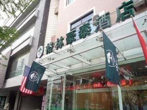 ein Gebäude mit zwei Flaggen davor in der Unterkunft GreenTree Inn Jiangsu Suzhou Shi Road North Tongjing Road Subway Station Express Hotel in Suzhou