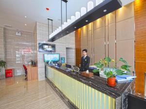 a man standing at a counter in a lobby at GreenTree Inn GuangDong JieYang Bus Terminal Station RongHua Avenue Business Hotel in Jieyang +80 photos