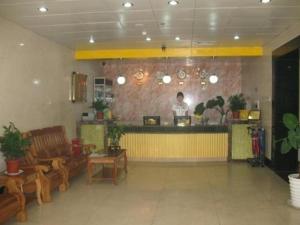 une femme debout derrière un bar dans un restaurant dans l'établissement GreenTree Inn West Railway Station North Square Hotel, à Pékin