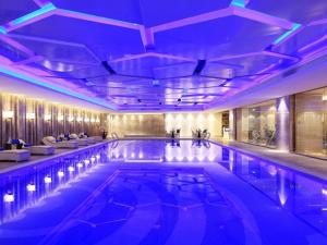 una piscina in un hotel con illuminazione viola di Wyndham Grand Plaza Royale Huayu Chongqing a Chongqing