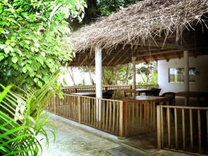 a patio with a straw roof and a table and chairs at Hotel Tangoreef in Tangalle